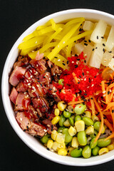 Hawaiian tuna poke bowl with rice on a black background
