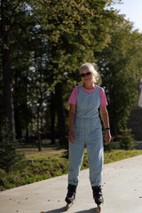 Obraz premium Middle-aged woman roller-skates in the city. Middle age entertainment.