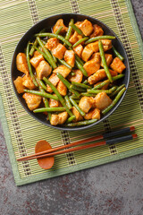 Pad Prik King chicken and crunchy long beans tossed in salty-sweet red curry paste closeup on the plate on the table. Vertical top view from above