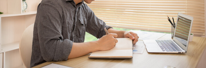 Man studies online on a laptop, Chat via laptop, Take notes, Learn online.