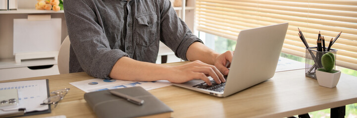 Man sitting and working in the office, Pressing laptop keyboard , Working in front of the laptop.