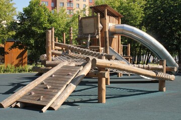 Wooden modern ecological safety children outdoor playground equipment in public park. Nature architecture construction playhouse in city. Children rest and childhood concept. Idea for games on air. - obrazy, fototapety, plakaty