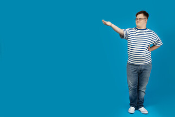 Smiling young man with down syndrome in glasses posing on blue background