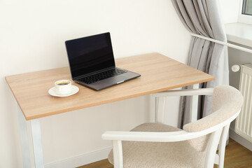 A cup of coffee and a laptop on the table