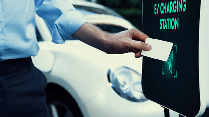 Businessman pay electric vehicle's eco-friendly and sustainable energy scanning credit card at...