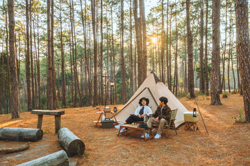 Asian couple enjoying morning coffee and nature view in the middle of the forest camping concept