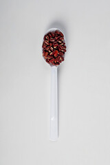Red kidney beans on spoon on white background