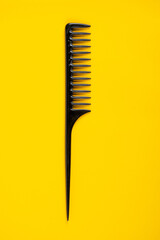 Black hair comb isolated on yellow background
