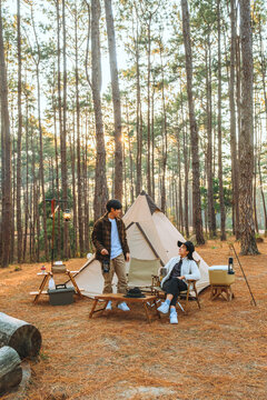 Asian couple enjoying morning coffee and nature view in the middle of the forest camping concept