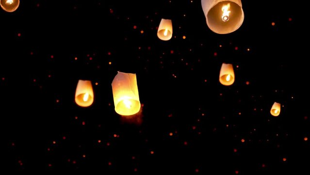 hand releasing floating lantern to the night sky with many paper  lanterns floating at background for Yi Peng tradition during Loy Kratong Festival at Chiang Mai, North of Thailand