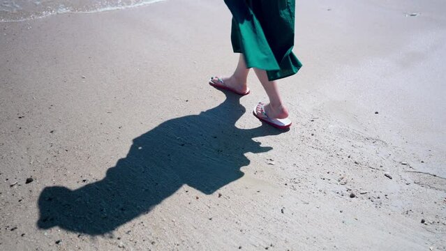 砂浜から海へ足を運び込む女性の下半身