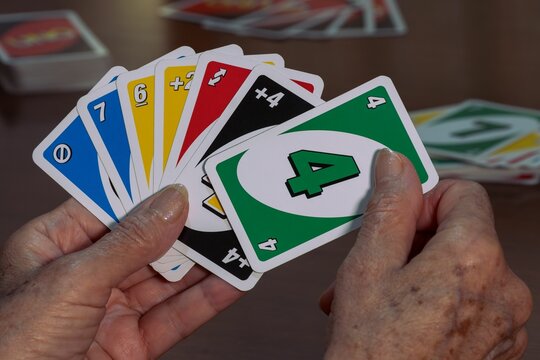 Closeup shot of the hands of an elderly woman holding UNO cards