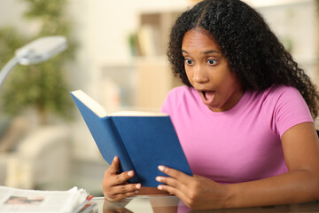 Amazed black woman reading a book at home