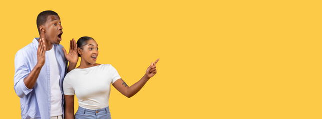 Surprised black man and woman pointing on yellow background