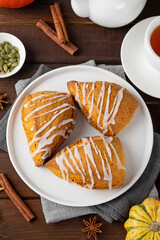 Traditional pumpkin scones with cinnamon, anise and sugar glaze on top. Autumn dessert.