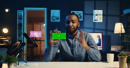 Happy content creator holding chroma key product, being sponsored by tech company to film unboxing...