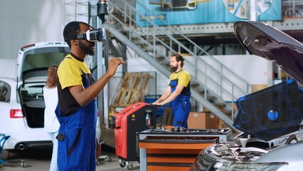 Mechanic in repair shop using advanced virtual reality technology to visualize car mechanical...