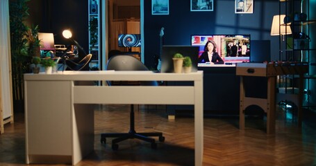 Dimly lit studio with professional recording devices used for internet show production. Apartment filled with tech equipment, TV running in background and 3D render animations on computer screens