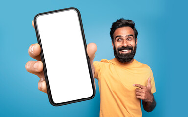 Middle Eastern man pointing at large smartphone screen, blue background - obrazy, fototapety, plakaty
