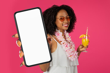 African woman holding large smartphone blank screen, pink studio background
