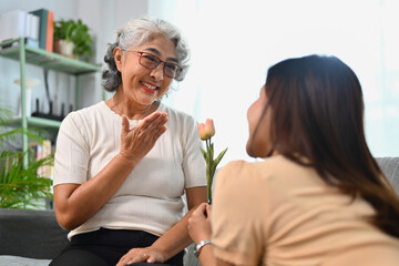 Grateful happy mature mother receiving flowers from grownup daughter. Happy Mothers Day concept