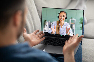 Man reclining on couch, using laptop, have online lesson