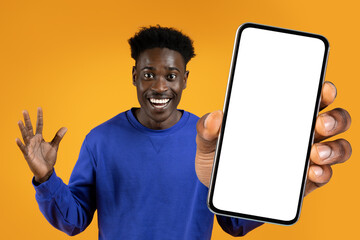 black guy offering huge smartphone with blank screen, orange backdrop