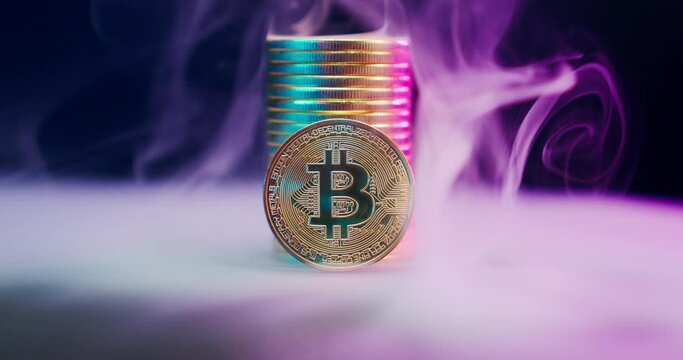 Bitcoin coins rotate around their axis in smoke.