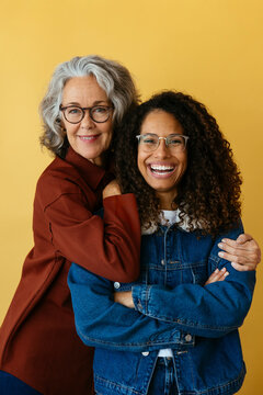 Happy mother embracing daughter against yellow background
