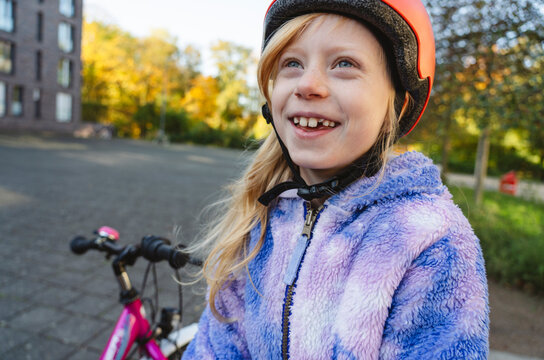 Smiling girl wearing helmet and contemplating near cycle