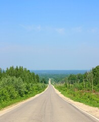 Fototapeta na wymiar Rural road in the green forest under the blue sky, Russia