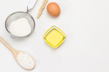 Flour in wooden spoon, sieve and glass jar. Olive oil and sprig of rosemary.