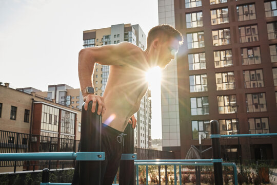 Shirtless man doing exercise on parallel bars
