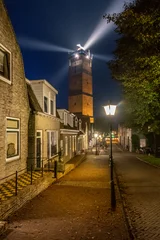 Fotobehang Lighthouse Brandaris at Terschelling with historic street and bright light beam © Thomas