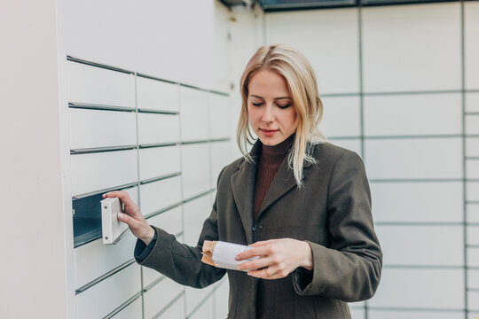 Woman picking up package from parcel locker