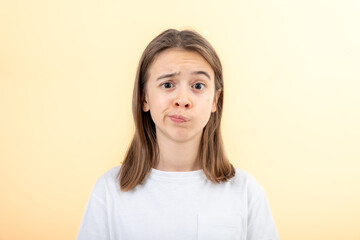 A teenage girl grimaces with displeasure on a white background, isolated. - obrazy, fototapety, plakaty