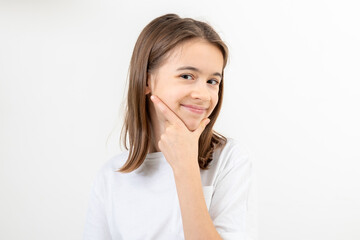 Fototapeta premium A schoolgirl thoughtfully holds her hand near her face on a white background.