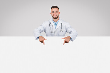 Doctor man pointing at empty white board below, grey background