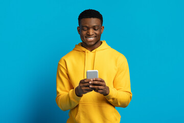 Portrait of happy smiling young black man using smartphone