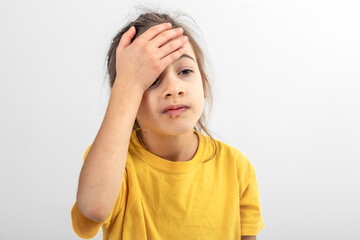 A little girl holds her palm on her face on a white background isolated.