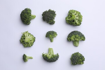 Many fresh green broccoli pieces on white background, flat lay