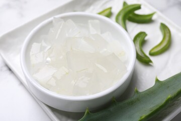 Aloe vera gel and slices of plant on white table, closeup