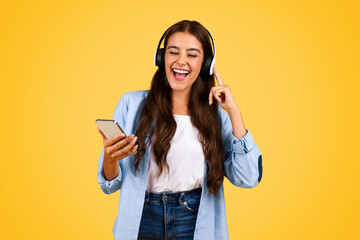 Happy teenager student woman typing on smartphone with headphones, sing song - obrazy, fototapety, plakaty