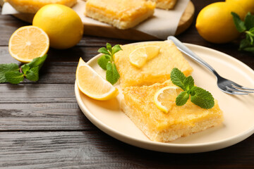 Tasty lemon bars served on wooden table, closeup. Space for text