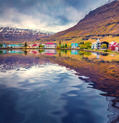 Seydisfjordur small town reflected in the caslm waters of Atlantic ocean. Dramatic  summer scene of...