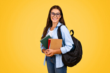 Smiling smart teenager european student woman in glasses, with backpack, books study