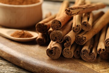 Obraz na płótnie Canvas Cinnamon powder and sticks on wooden table, closeup
