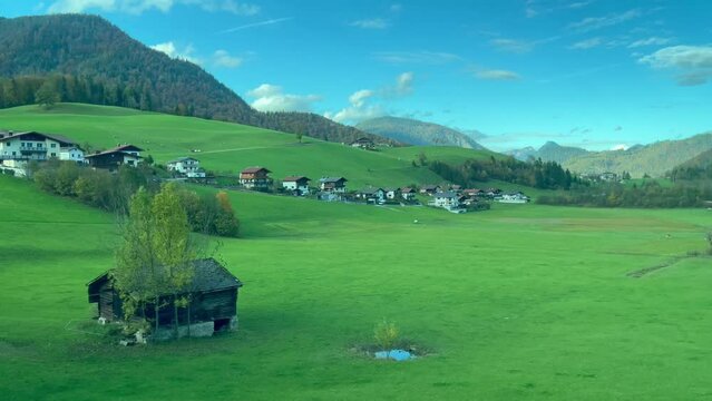 Green grass valley on countryside road trip in Austria. Alps mountains natural landscape view from car under blue sky