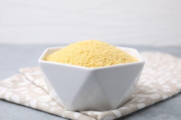 Raw couscous in bowl on table, closeup