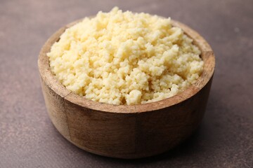 Tasty couscous in bowl on brown table, closeup
